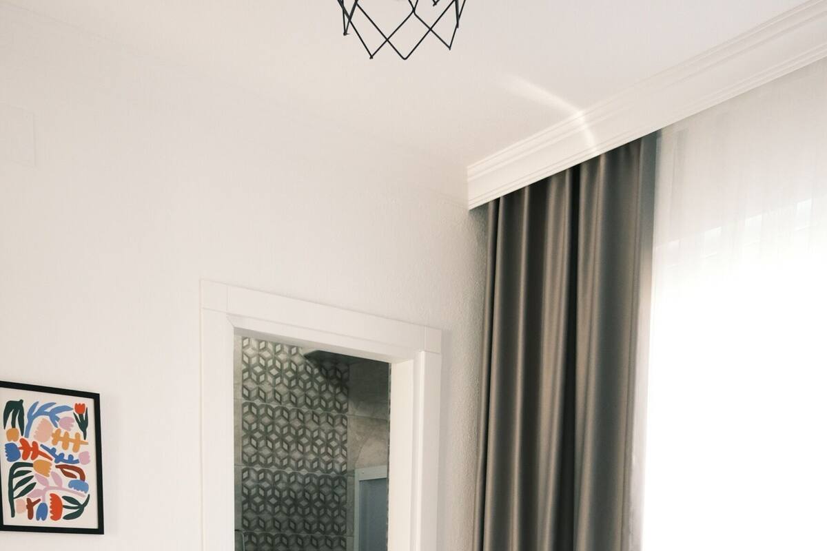 Een hotelkamer met een bed, twee opgerolde handdoeken, een badkamer zichtbaar door een open deur, en een afbeelding in een lijst aan de muur.