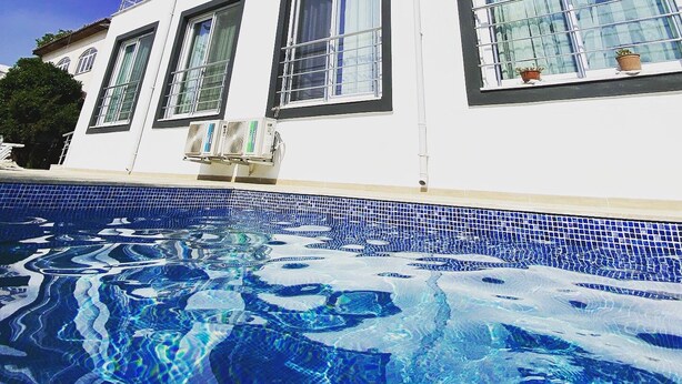 Um edifício moderno e branco com uma piscina em frente.