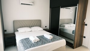 Quarto de hotel moderno com uma cama grande, mesa de cabeceira, guarda-roupa e espelho.