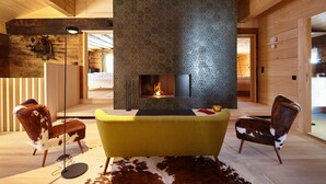 A modern interior with a fireplace, wooden walls, and two chairs. - Haus Obdr Lech in Lech (Lech am Arlberg)