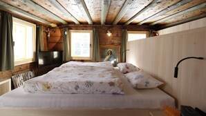 A wooden cabin bedroom with a bed, a television, and a portrait on the wall. - Haus Obdr Lech in Lech (Lech am Arlberg)