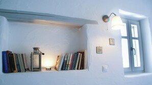 A bookshelf with books and a metal lantern, a wall-mounted light fixture, and a window with a door. - House with private pool (Kamares Naousas)