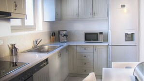 A modern kitchen with white cabinets, stainless steel appliances, and a built-in microwave. - House with private pool (Kamares Naousas)