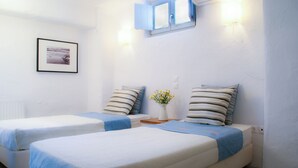 A room with two beds, a framed picture on the wall, and a small table with a vase of flowers. - House with private pool (Kamares Naousas)