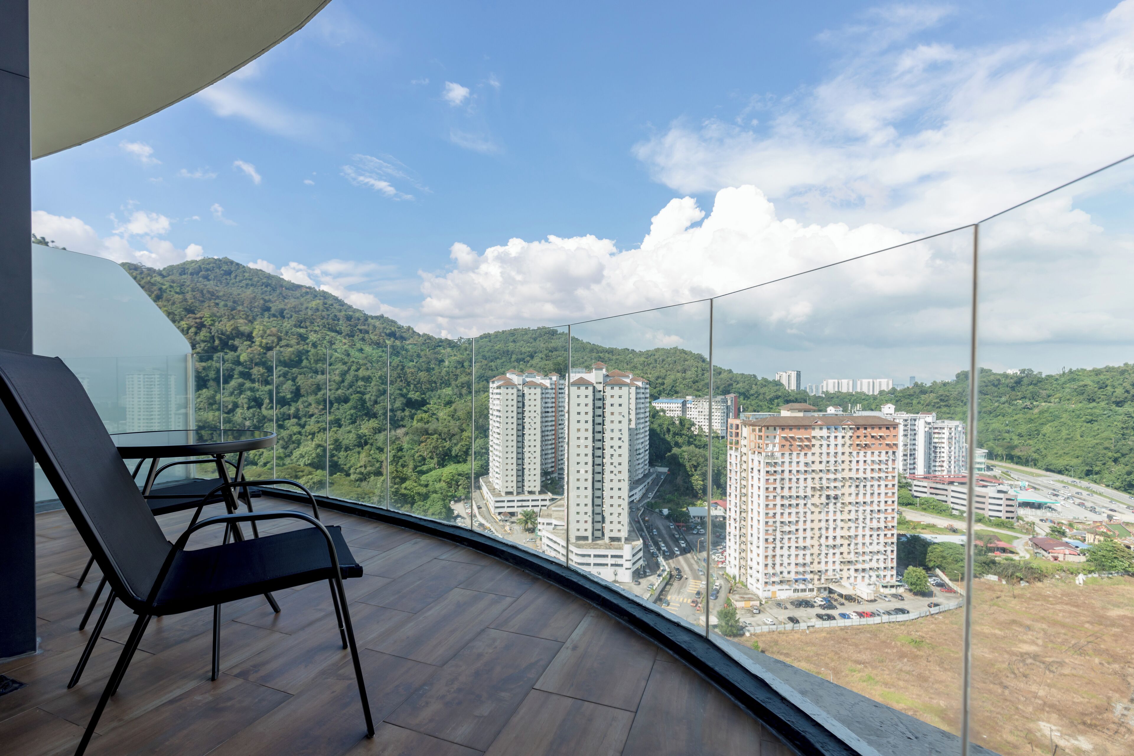 Ein Balkon mit Blick auf hohe Gebäude und einen bewaldeten Hügel.