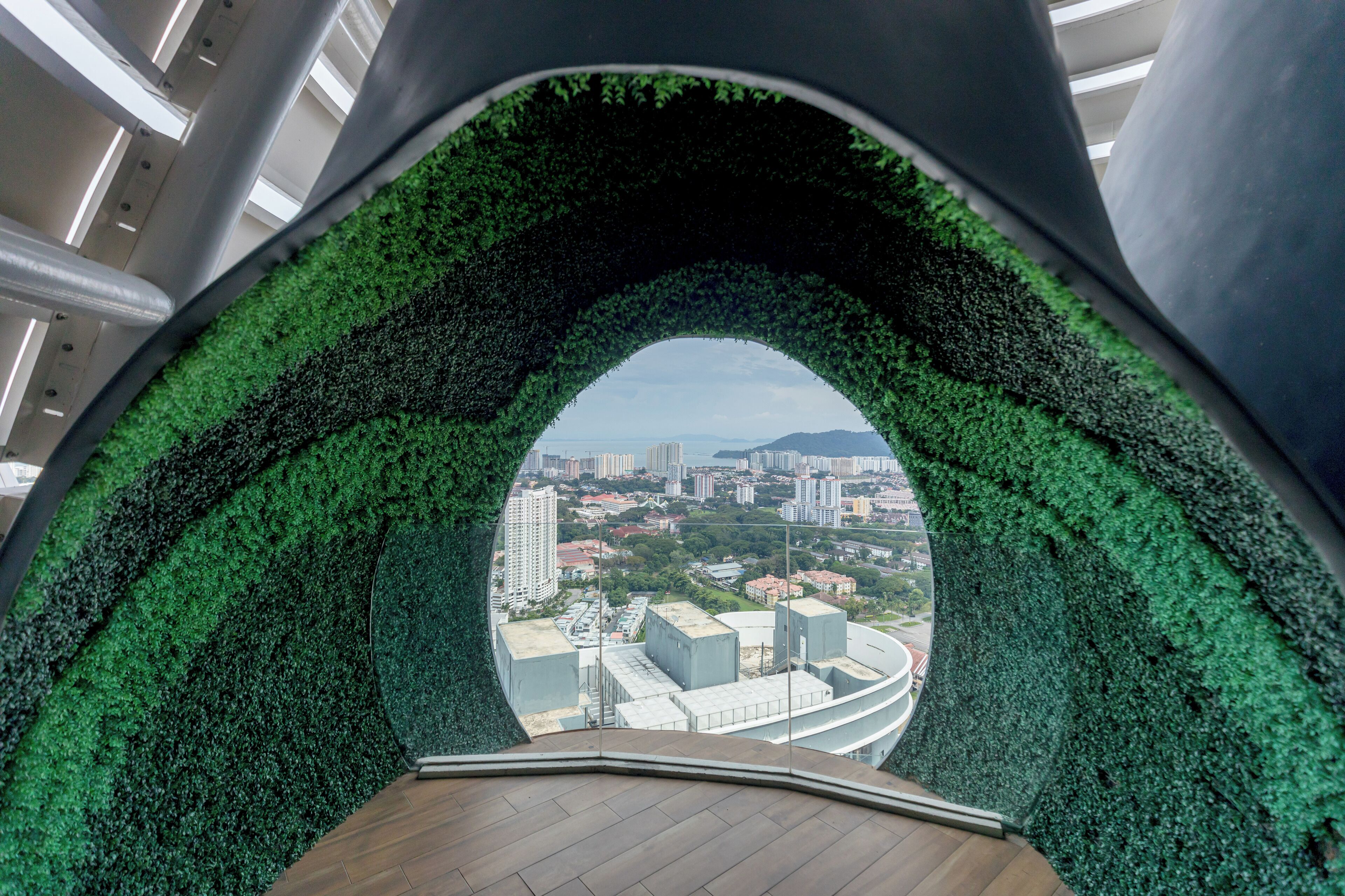 A circular viewing area with a green wall and a cityscape view.