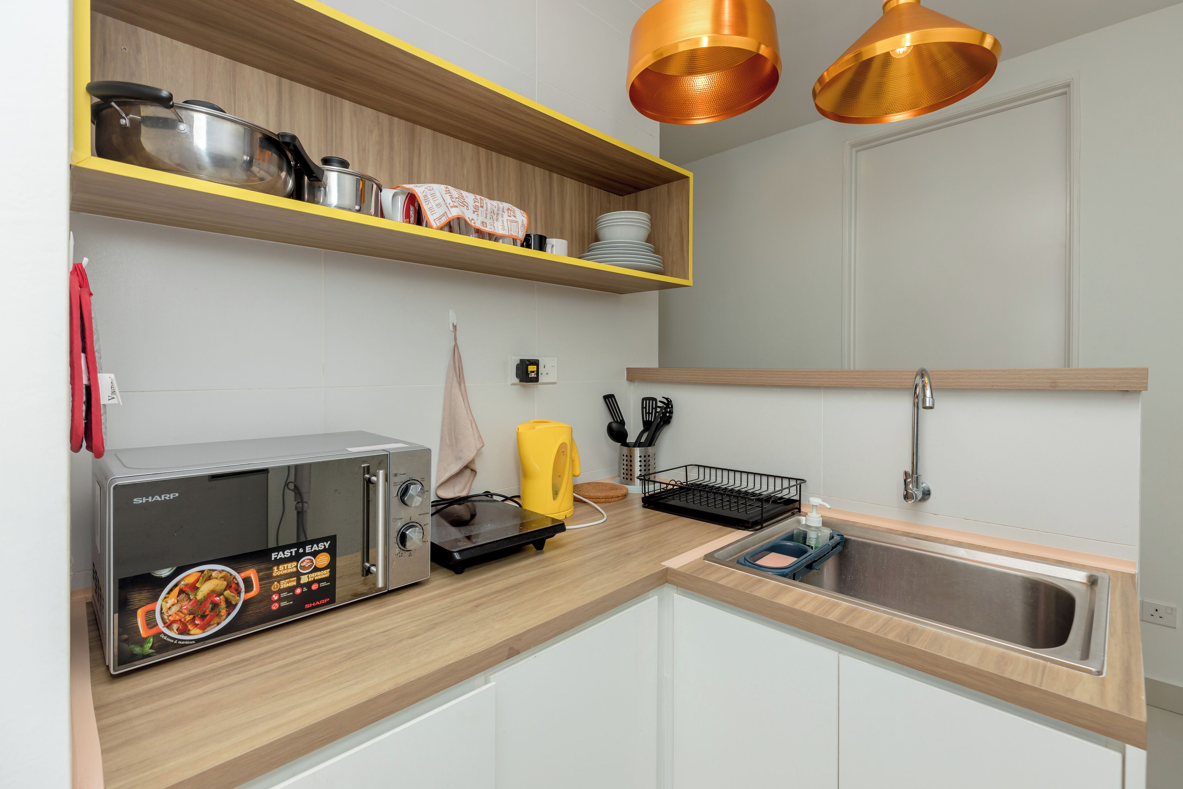 A modern kitchen with a microwave, toaster, and wooden shelves.