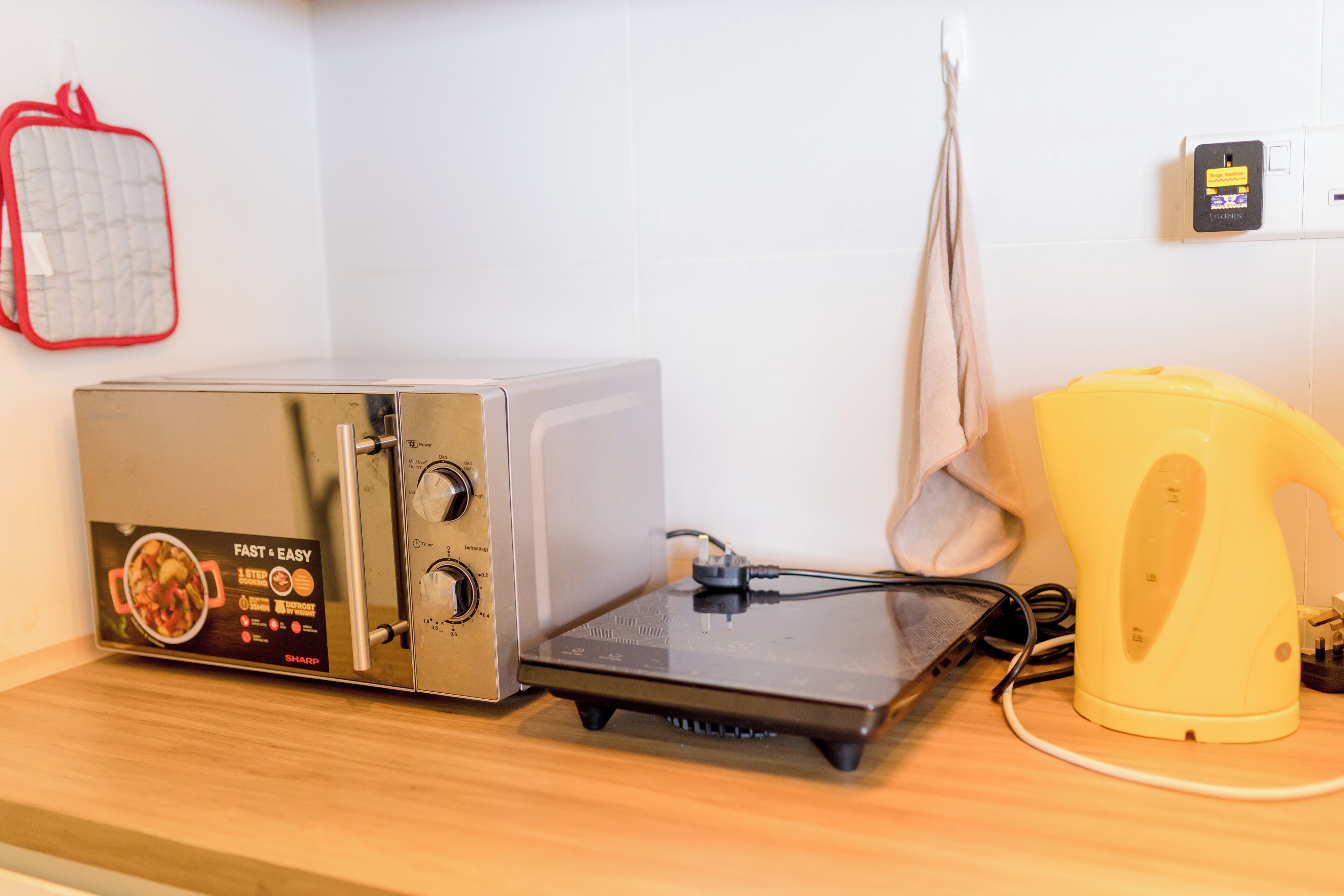 A kitchen with a toaster oven, a kettle, and a red oven mitt on the counter.