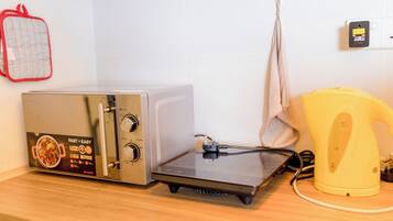 A kitchen with a toaster oven, a kettle, and a red oven mitt on the counter.