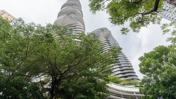 A modern building with a unique curved design, surrounded by lush green trees. - ArteS Suite Penang (George Town)
