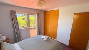 A bedroom with a bed, a window with curtains, a wardrobe, and a door.