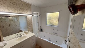Ein Badezimmer mit großem Spiegel, Waschbecken, Badewanne und Fenster.