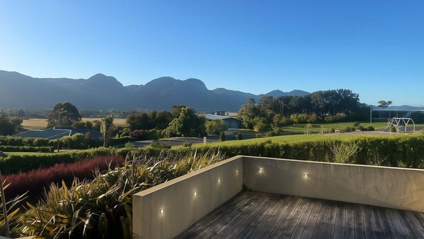Terraço no telhado com vista para montanhas distantes, um jardim ajardinado e um edifício com design moderno.