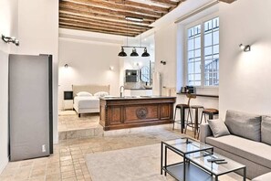 Ein modernes Interieur mit Küche, Essbereich und Wohnbereich, inklusive Holzboden, großer Fenster und zeitgemäßer Einrichtung.