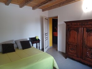 Ein Schlafzimmer mit Bett, Nachttisch, Kleiderschrank und einer offenen Tür zu einem anderen Raum.