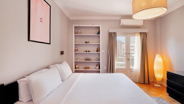 A hotel room with a large bed, a bookshelf, a dresser, and a window with curtains. - Brassbell Zamalek Nagui (Cairo)