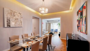 A modern dining area with a glass table, beige chairs, and a chandelier. - Brassbell Zamalek Nagui (Cairo)