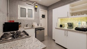 A modern kitchen with granite countertops, a gas stove, a dishwasher, and white cabinetry. - Brassbell Zamalek Nagui (Cairo)