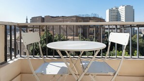 A balcony with a white table and two chairs, overlooking a cityscape with buildings and greenery. - Brassbell Zamalek Nagui (Cairo)