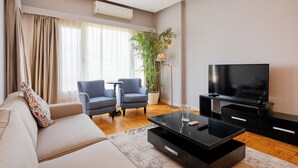 A modern living room with a sofa, two armchairs, a coffee table, a TV, and a potted plant. - Brassbell Zamalek Nagui (Cairo)