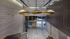 Een modern interieur met een marmeren trap, een centrale plant en een uniek lichtarmatuur.