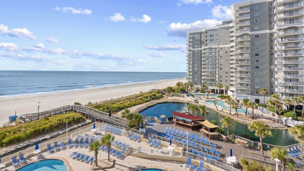 A resort with multiple swimming pools, a beach, and high-rise buildings.