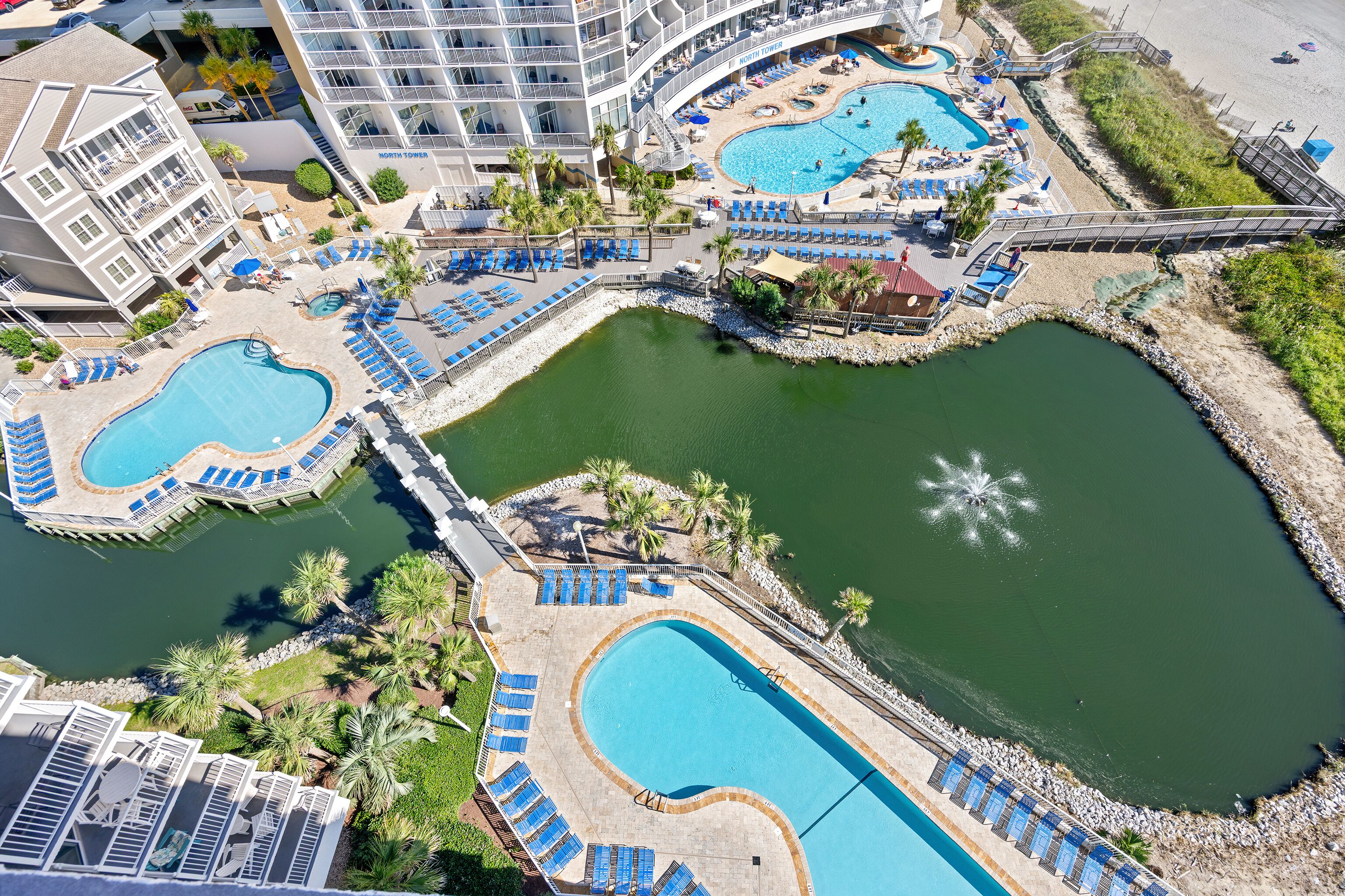 Un resort con varias piscinas, tumbonas y un puente que conecta diferentes zonas.
