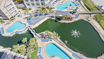 Un resort con varias piscinas, tumbonas y un puente que conecta diferentes zonas.