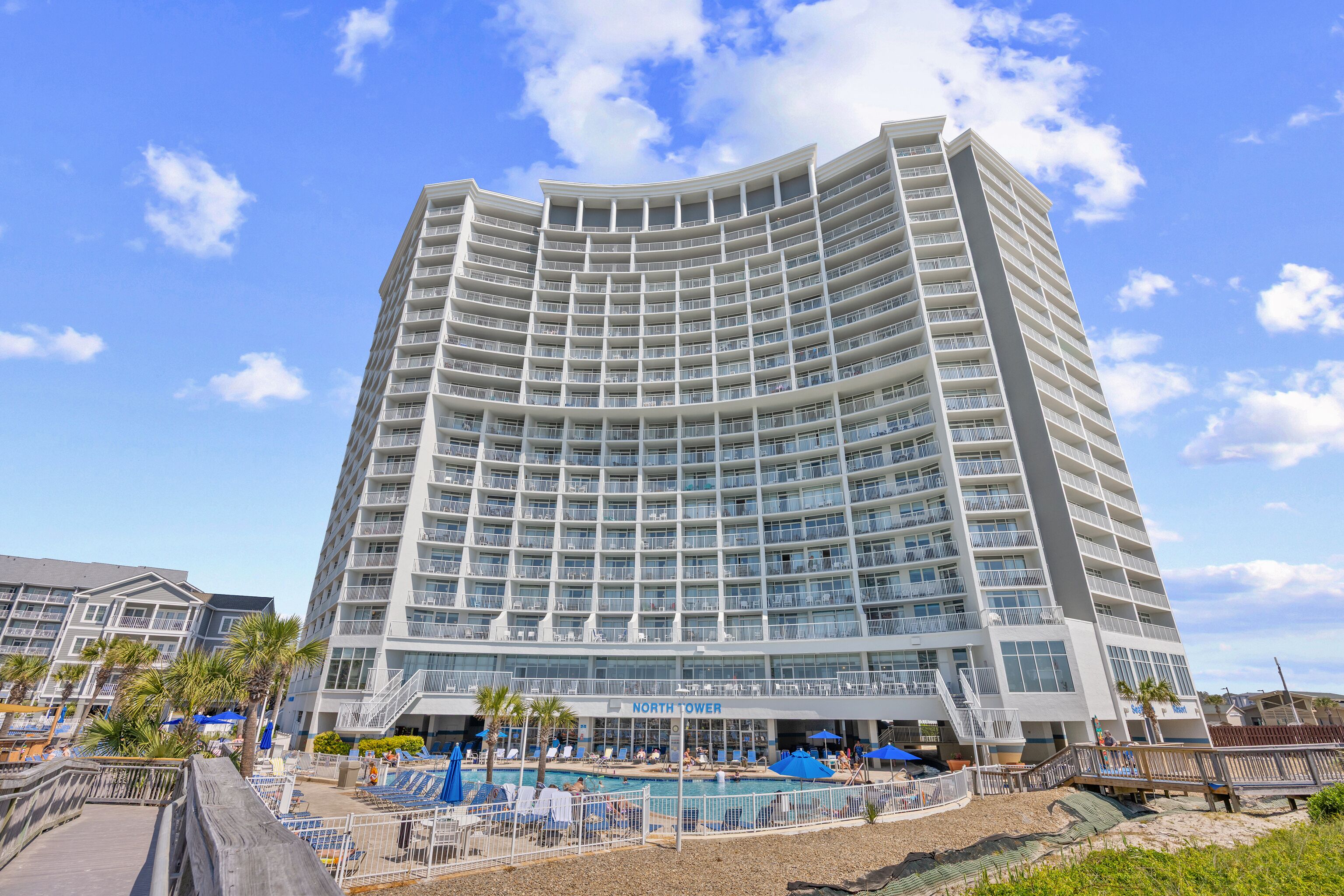 Un hotel de varios pisos con área de piscina, asientos al aire libre y un letrero que dice 'North Tower'.