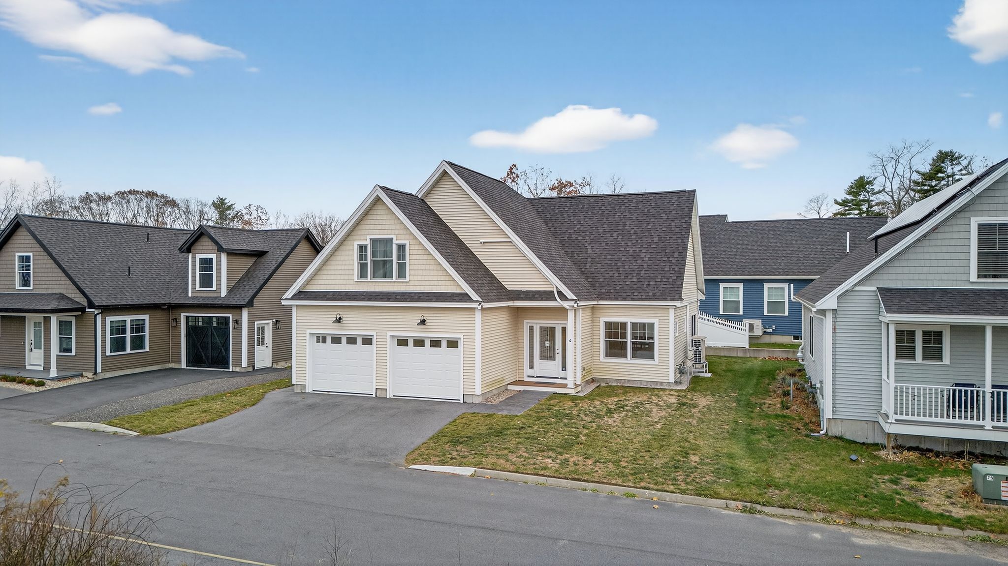 A row of single-family homes with attached garages, a well-maintained lawn, and a clear sky.