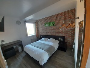 A modern bedroom with a brick wall, a bed, a window, a desk, and a radiator. - Hotel Rooms in Downtown Amiens (Amiens)