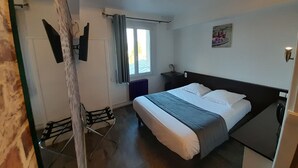 Une chambre d’hôtel avec un lit, une chaise, un radiateur, une fenêtre avec des rideaux et un tableau accroché au mur.