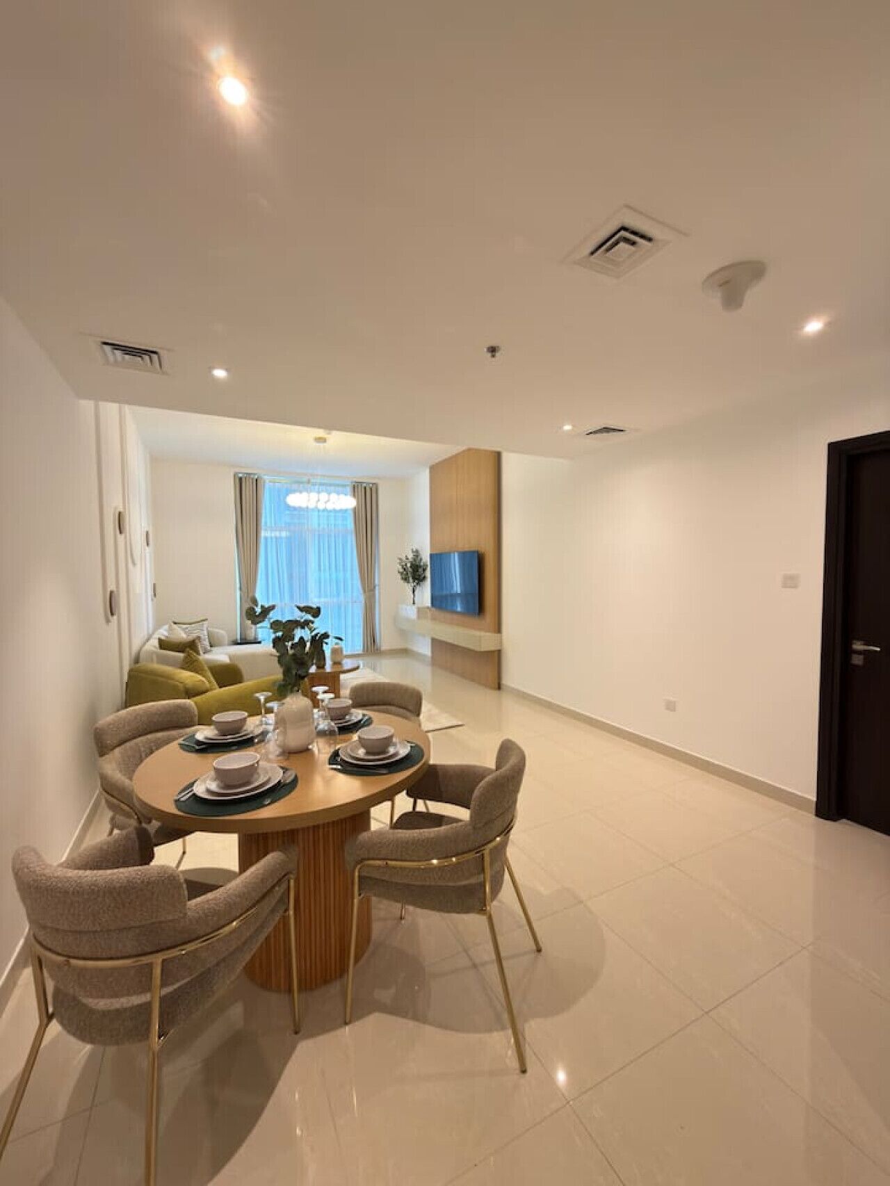 Un espace repas moderne avec une table ronde, quatre chaises et un téléviseur fixé au mur.