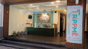 A reception desk with a glass partition, a chandelier, and a sign advertising rooms, forms, and a cafe.