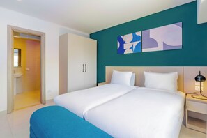 Ein modernes Hotelzimmer mit einem großen Bett, einem Kleiderschrank, einem Badezimmer und abstrakter Wandkunst.