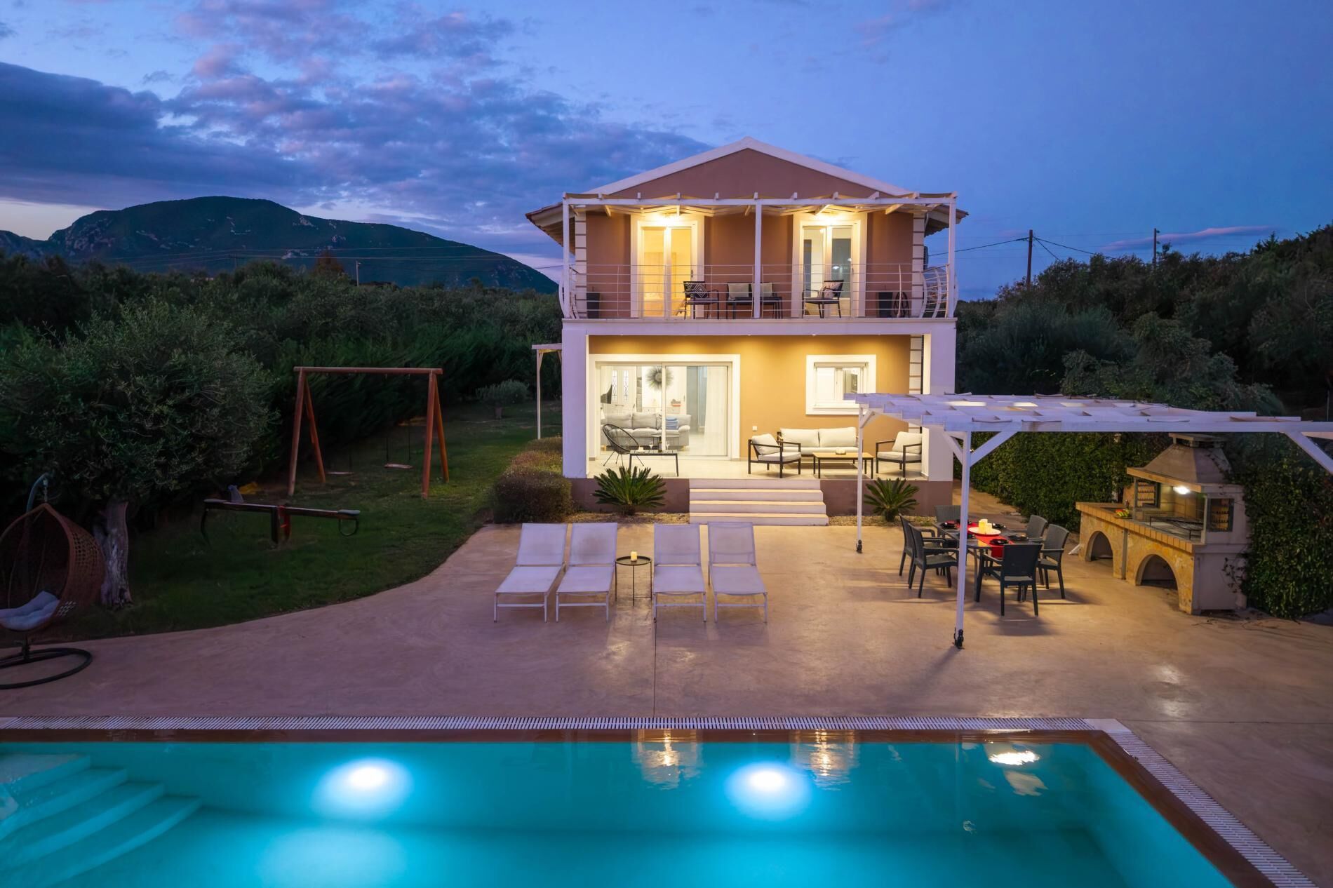 Una casa de dos pisos con balcón, piscina y mobiliario exterior.