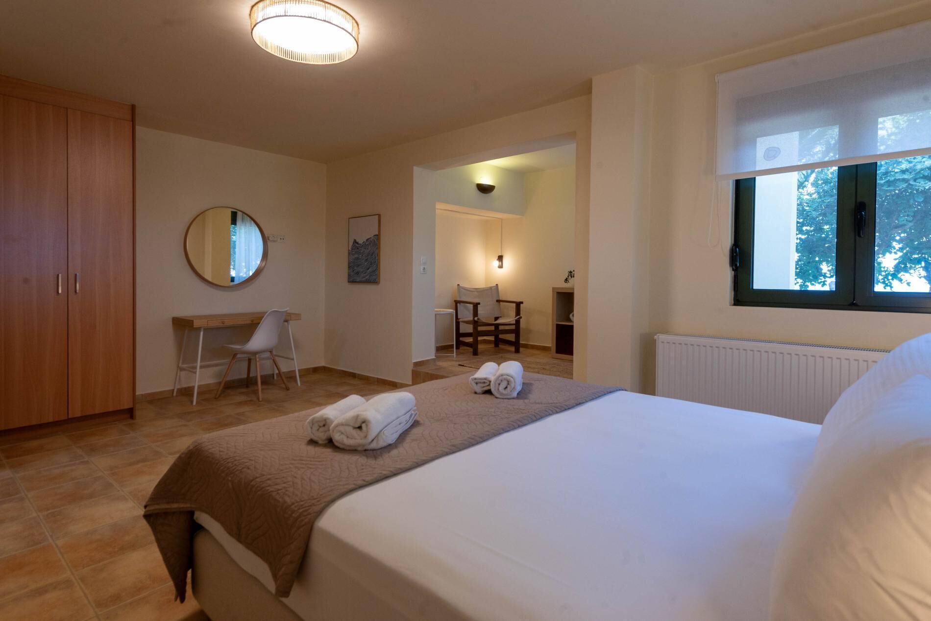 A bedroom with a bed, a desk, a chair, a wardrobe, and a window.