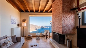 Un salon chaleureux avec une cheminée, un canapé, une table à manger et une vue sur la mer.
