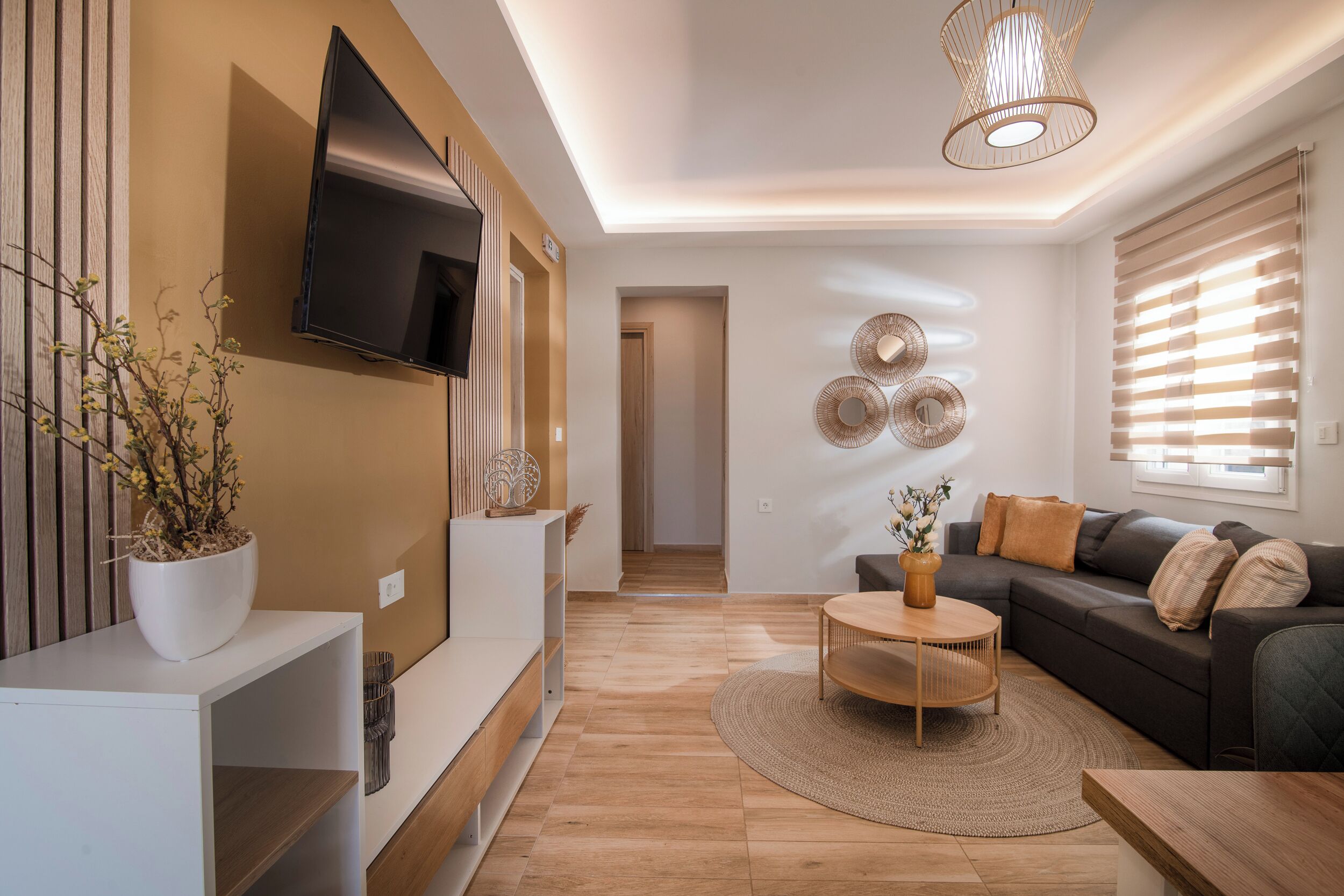 A modern living room with a flat-screen TV, a sofa, a coffee table, and decorative wall art.