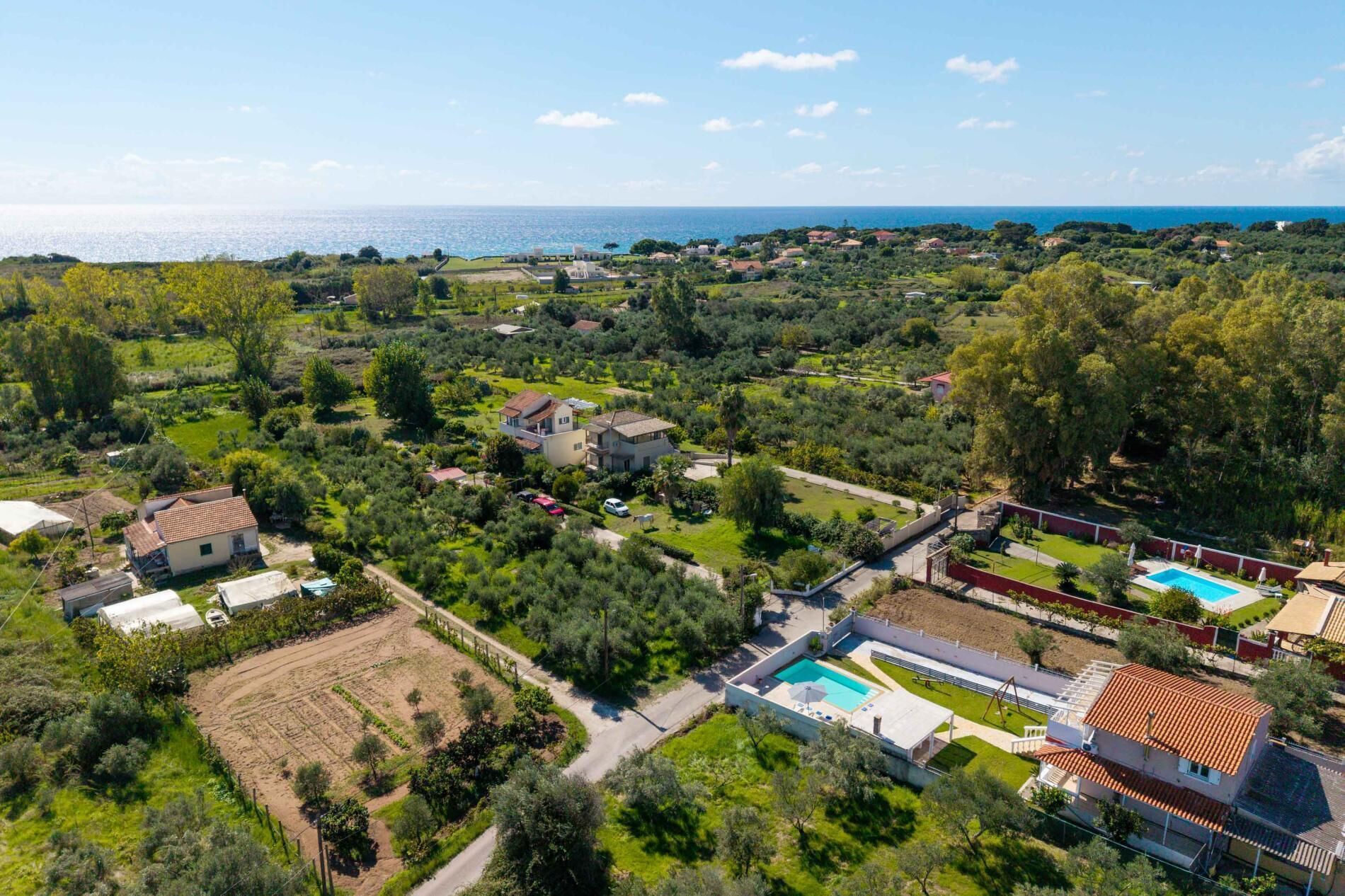Vista aérea de una zona residencial con casas, una piscina y vistas al mar.