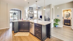 A modern kitchen with dark cabinetry, a large island, pendant lighting, and a view to the living area. - 4,500-sq-ft Retreat w/ Hot Tub in Colorado Springs (Colorado Springs)