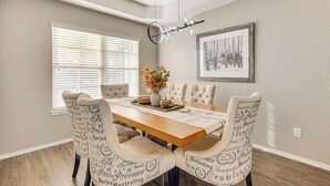 A dining area with a wooden table, cushioned chairs, a vase with flowers, and a framed picture on the wall. - 4,500-sq-ft Retreat w/ Hot Tub in Colorado Springs (Colorado Springs)