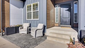 A house with a grey exterior, a front door, and two wicker chairs on a concrete patio. - 4,500-sq-ft Retreat w/ Hot Tub in Colorado Springs (Colorado Springs)