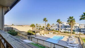 A pool area with lounge chairs, a pergola, and a view of a beachfront property. - Steps to Sand: Breezy Port Aransas Condo! (Port Aransas)