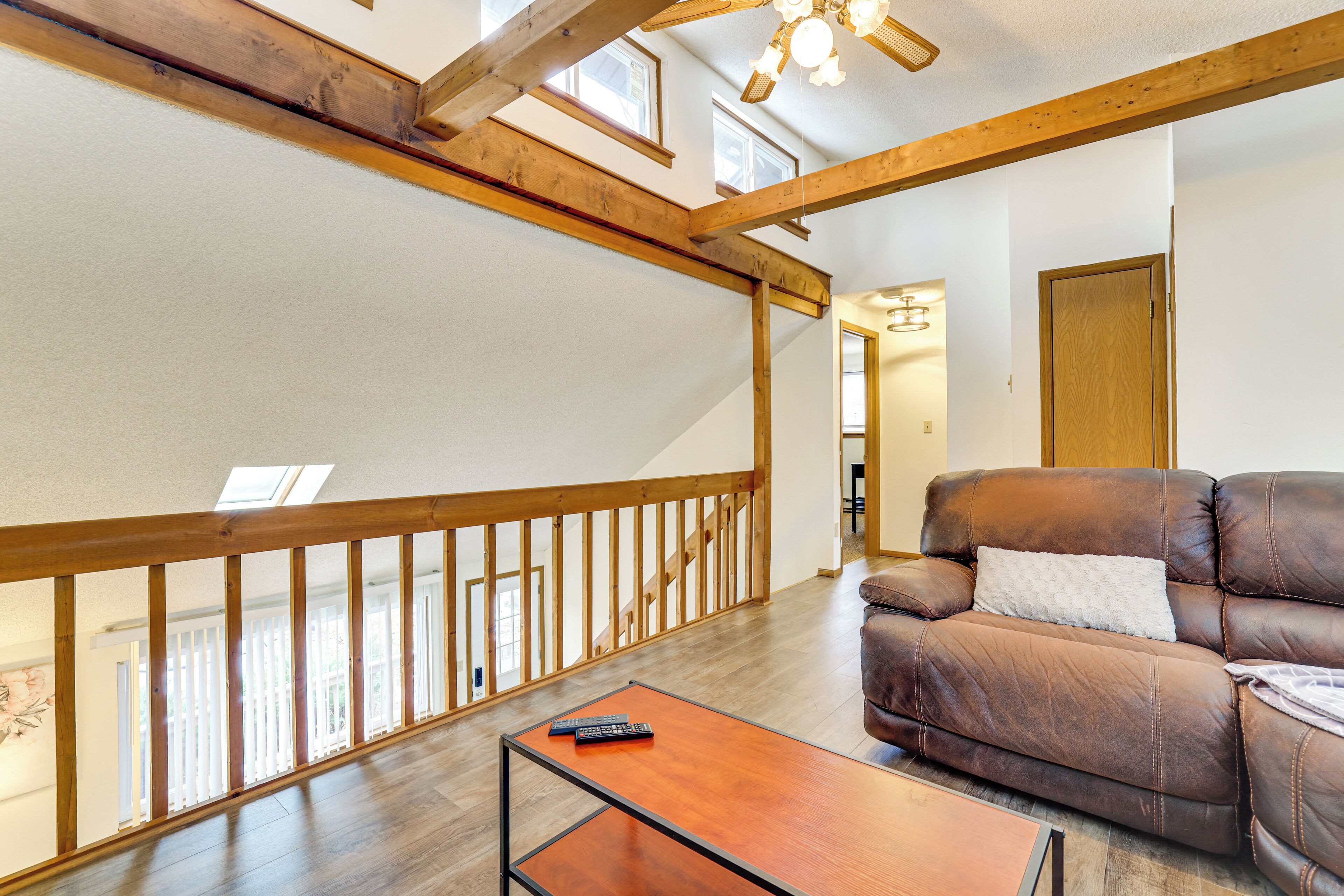 A spacious living area with a wooden ceiling, a brown leather sofa, and a wooden coffee table.