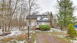 A two-story house with a covered porch, surrounded by trees and a gravel path. - Ski, Swim & Hike! Family Home in Tobyhanna (Tobyhanna)