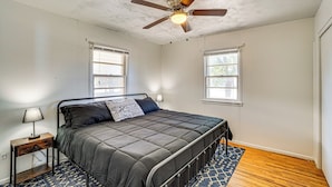 A bedroom with a bed, a ceiling fan, two windows, a nightstand, and a patterned rug. - Near Hunting Grounds: Aspermont Home w/ Yard (Aspermont)
