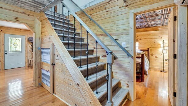 A wooden interior with a staircase, wooden floors, and a door leading to a bedroom. - Big South Fork National River and Recreation Area (Oneida)