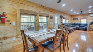 A wooden cabin interior with a dining table, chairs, a leather sofa, and a ceiling fan. - Big South Fork National River and Recreation Area (Oneida)