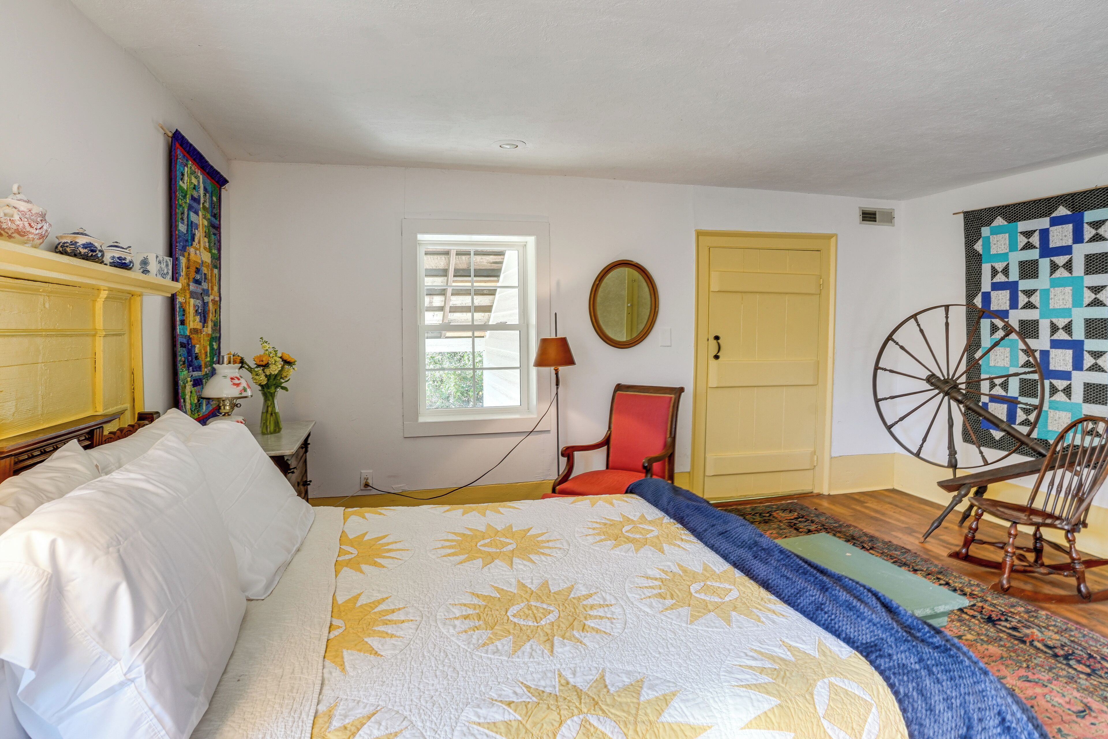 A bedroom with a bed, a chair, a lamp, a window, and a door.